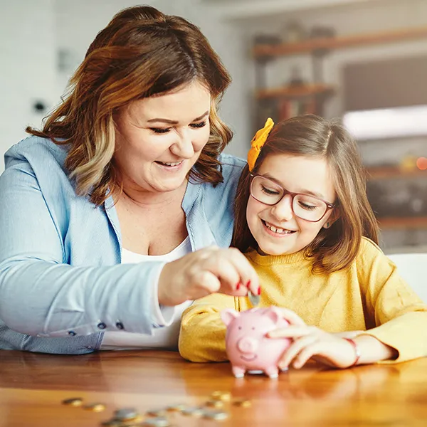 mother and daughter putting coins in piggy bank