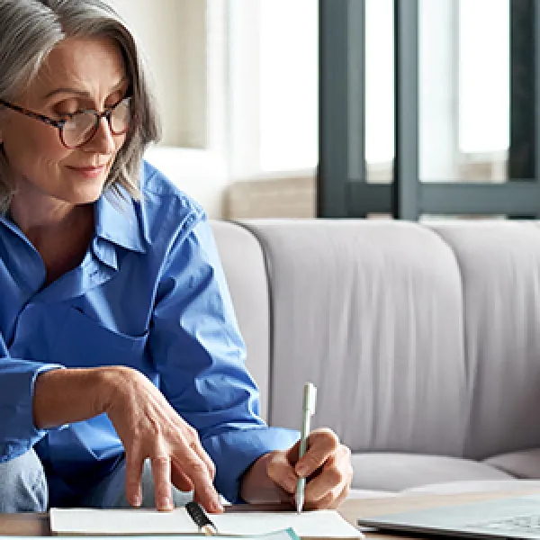woman-looking-at-laptop-taking-notes