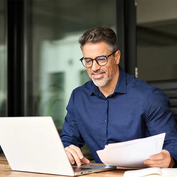 Man using laptop and reviewing documents